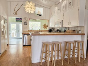 A kitchen with white cabinets, a wooden countertop, and four wooden stools. - Blue Anchor Charming Beach Cottage. Short Walk to  Beach, North Litchfield (Pawleys Island)