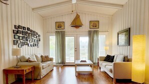 Ein geräumiges Wohnzimmer mit Holzboden, zwei Sofas, einem Couchtisch und einer Wand mit gerahmten Bildern.