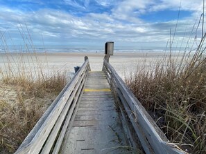 A wooden boardwalk leading to a beach with a wooden structure in the distance. - Blue Anchor Charming Beach Cottage. Short Walk to  Beach, North Litchfield (Pawleys Island)