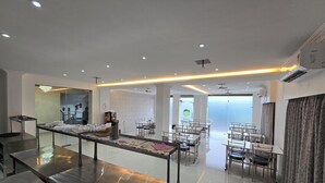 Un comedor moderno con mesas y sillas, una recepción y un separador de vidrio.