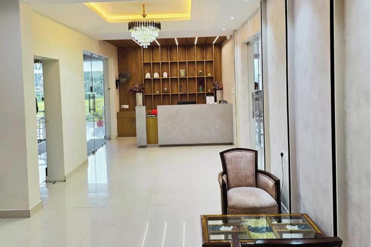 A hotel lobby with a reception desk, a chandelier, a glass coffee table, and a wooden reception area.