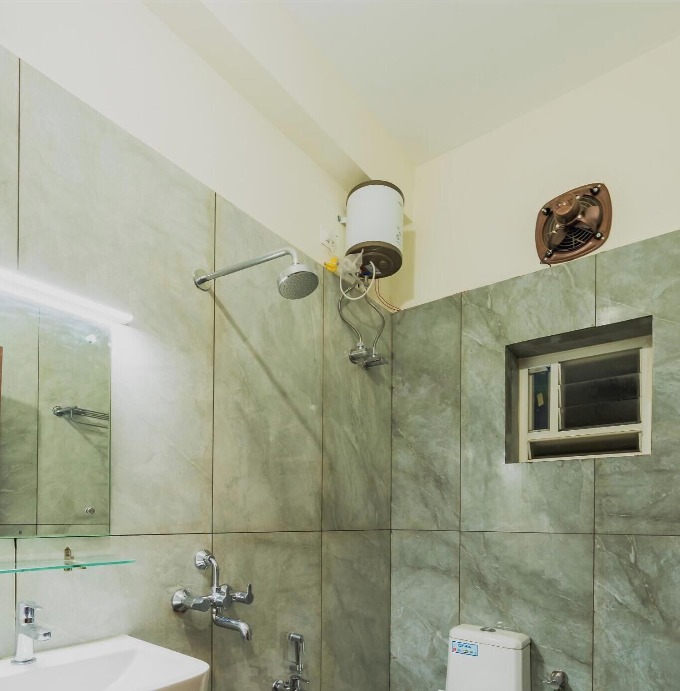 A bathroom with a shower, a sink, a mirror, and a fan.