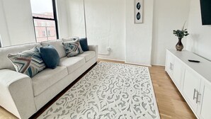 Ein modernes Wohnzimmer mit einer Couch, einem gemusterten Teppich und einem weißen Schrank.