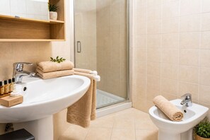 A bathroom with a large sink, a smaller sink, a shower, and a toilet. There are towels and toiletries on the sink. - Centro Storico Savona - Porto Crociere 2 (Savona)