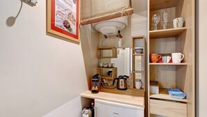 Uma cozinha compacta com geladeira, cafeteira, chaleira e uma pia pequena.