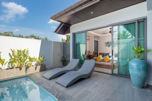 A modern outdoor pool area with lounge chairs, a large blue vase, and a sliding glass door leading to a living area. - Nicky Serene 3BR Pool Villa (Choeng Thale)