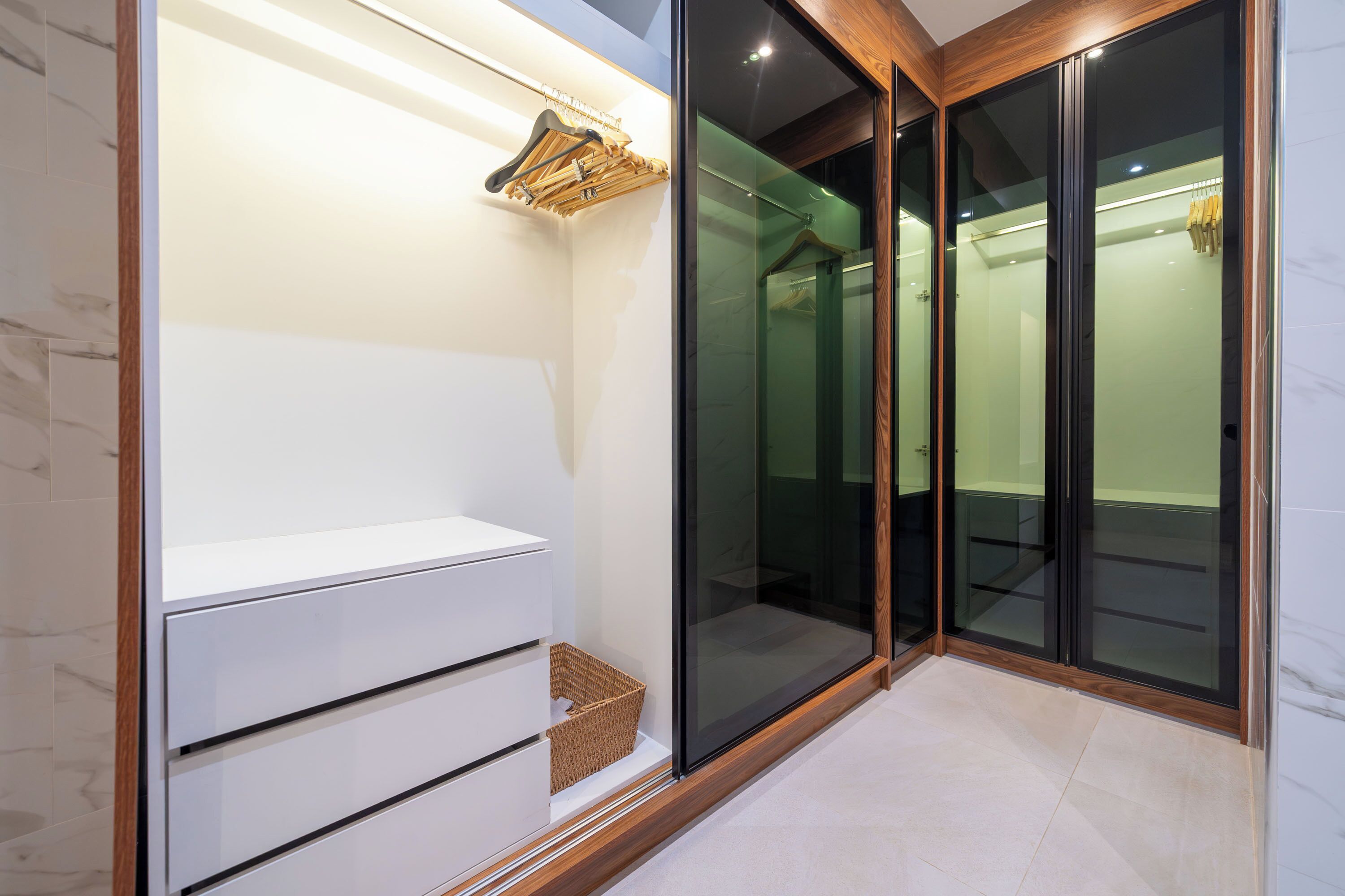 Een moderne badkamer met een douchecabine van glas, een witte bank en een wastafelmeubel met houten frame.