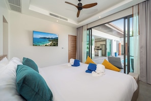 A hotel room with a bed, a ceiling fan, a painting of a beach, and a view of the outside. - Nicky Serene 3BR Pool Villa (Choeng Thale)
