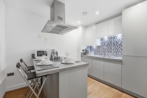Eine moderne Küche mit Kochinsel, Edelstahlgeräten und einer gefliesten Spritzschutzwand.
