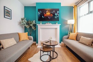 Ein Wohnzimmer mit Kamin, zwei Sofas, einem Fernseher und einer Lampe.
