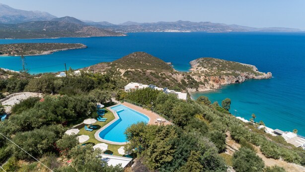 Un resort con piscina, sillas de descanso y vistas al mar y a las montañas.
