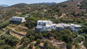 Una villa moderna con varios niveles, piscina y vistas del paisaje montañoso circundante.