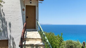 A coastal building with a wooden door, a stone staircase, and a view of the sea. - Maisonette (split-level apartment) with sea view, Wi-Fi, and air conditioning (Agios Nikolaos)