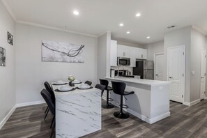 A modern kitchen with white cabinets, a marble countertop, and black bar stools. - Luxury 2-bedroom Condo with AC in lovely Scottsdale (Scottsdale)