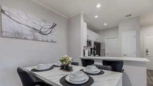 A dining area with a marble table, black chairs, and a vase of flowers.