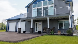 En tvåvåningsbyggnad med ett garage, en inglasad veranda och en liten uteplats.