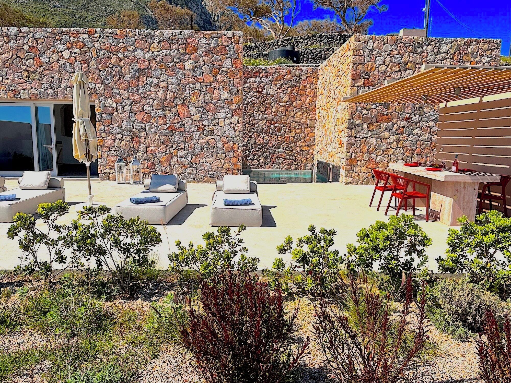 Un muro de piedra, asientos exteriores y una zona de bar.