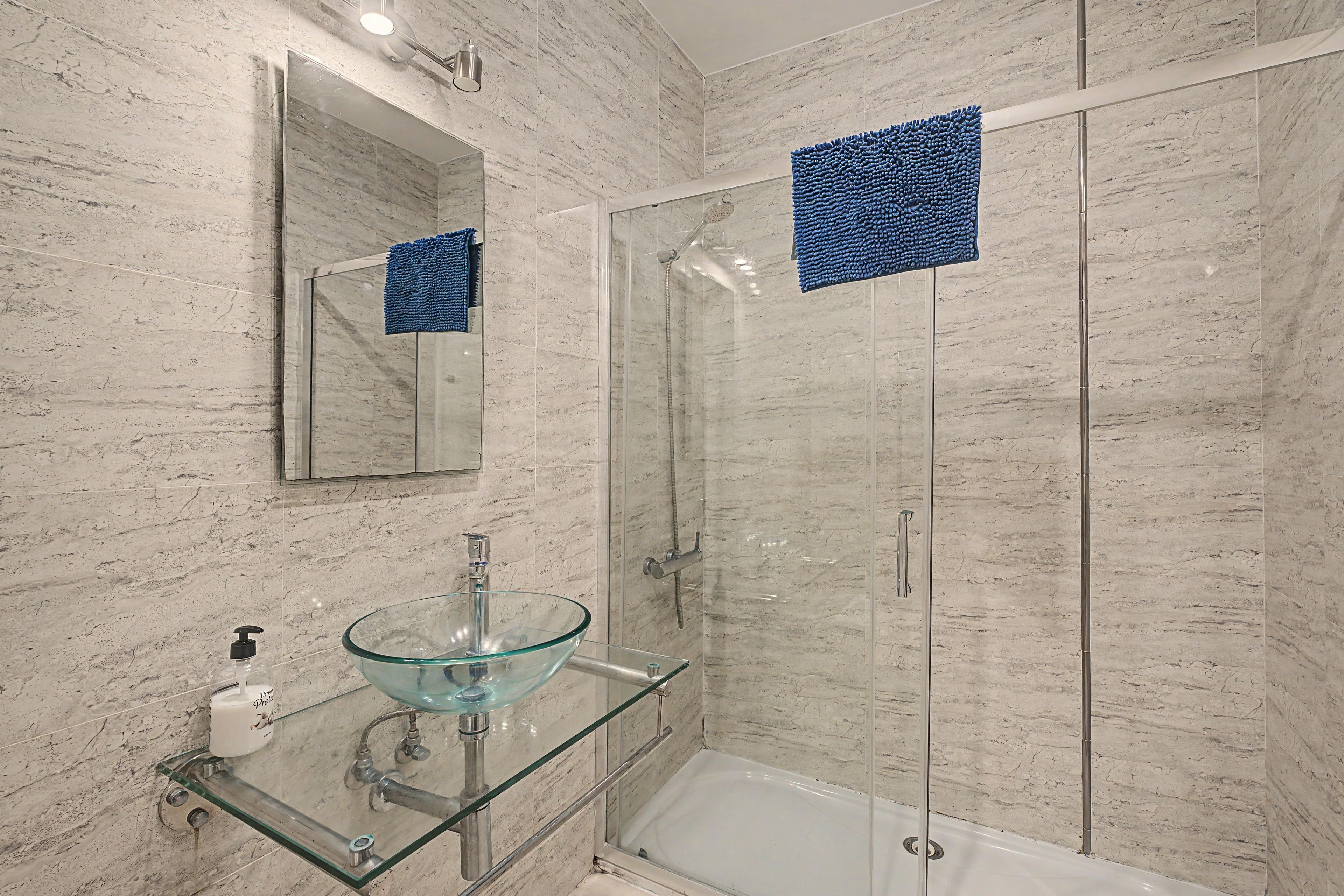 Ein modernes Badezimmer mit einem Glaswaschbecken, einer Handbrause und einer Duschkabine aus Glas.