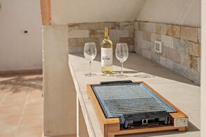 A stone wall with a wine bottle and glasses on a table. - Casa Orquidea Sea View Chalet with Pool & Rooftop Terrace in Quiet Coastal Area, Pelada Beach. (El Médano)