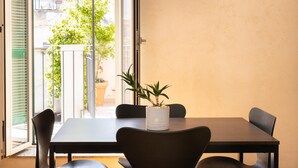 Ein Essbereich mit Tisch, Stühlen, einem Blumentopf und Blick durch eine Glastür.