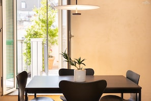 A dining area with a table, chairs, a potted plant, and a view through a glass door. - Pigneto Terrace Apartment (Rome)