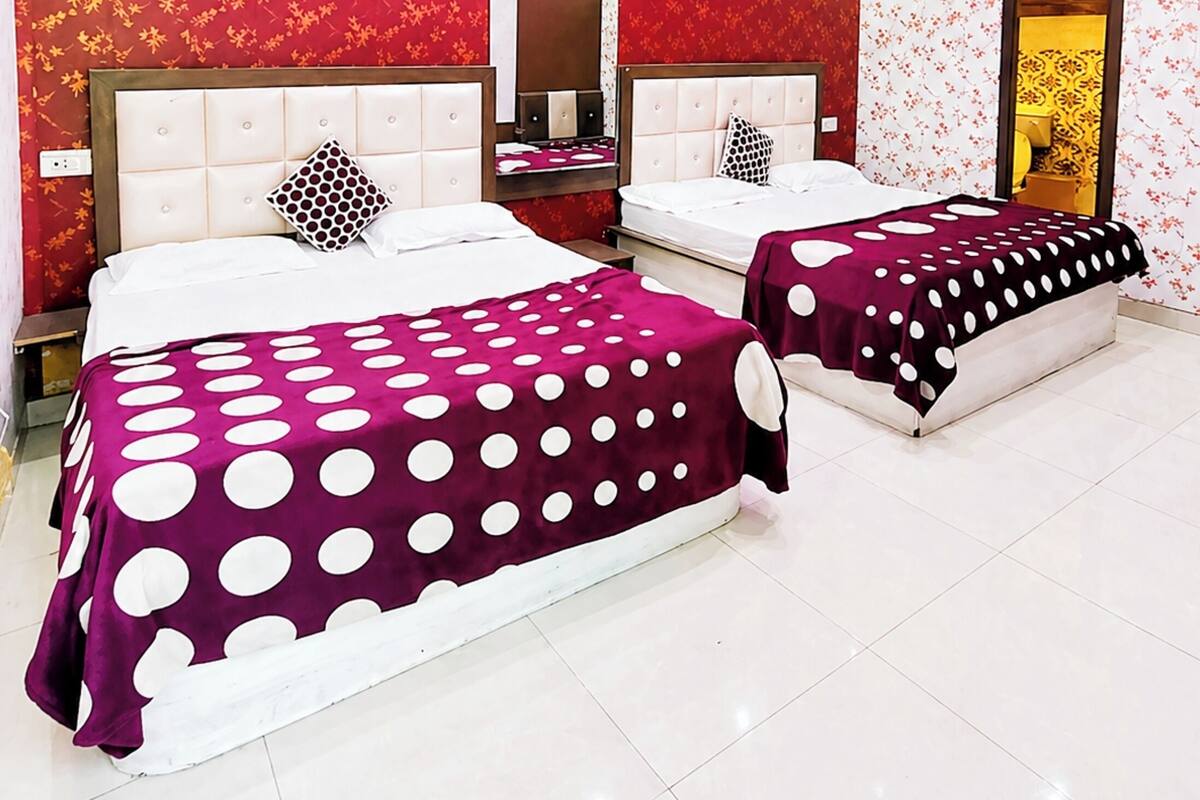 A hotel room with two beds, a large mirror, and a ceiling with pink lighting.