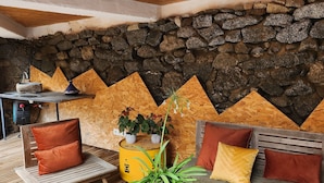 A cozy outdoor seating area with a stone wall backdrop, wooden furniture, and a potted plant. - In the heart of Font Romeu, a lovely house. (Font-Romeu-Odeillo-Via)
