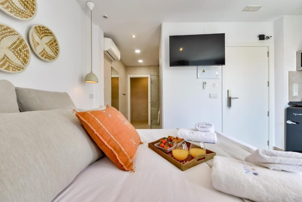 A hotel room with a bed, a TV, a tray of breakfast, and a door leading to a bathroom.