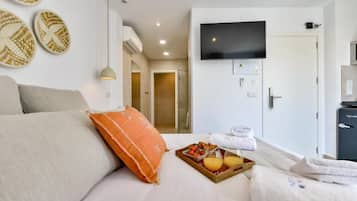 A hotel room with a bed, a TV, a tray of breakfast, and a door leading to a bathroom.