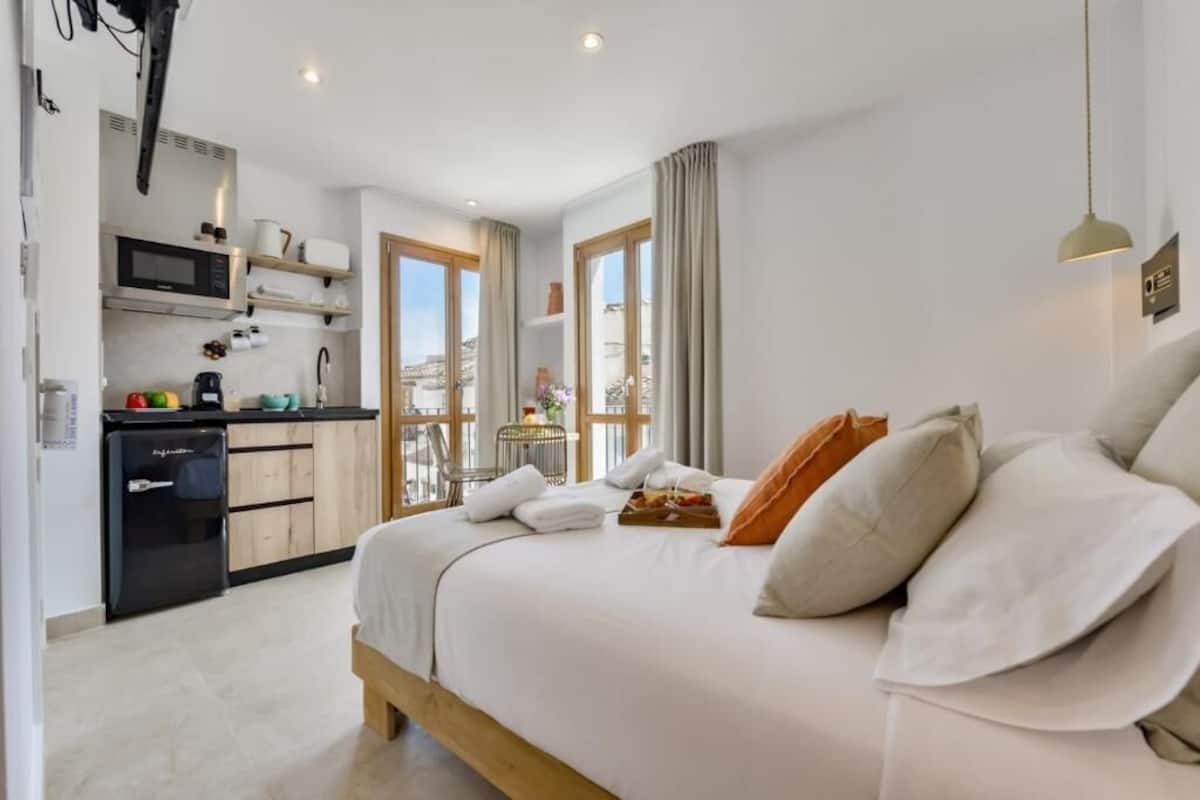 Une chambre d’hôtel comprenant un lit, une kitchenette, un coin repas et une vue sur la ville.