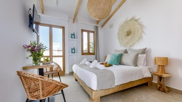 Un dormitorio con cama, mesita de noche, lámpara y una silla.