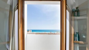 Un balcón con vistas al mar, un marco de puerta de cristal y una estantería con adornos.