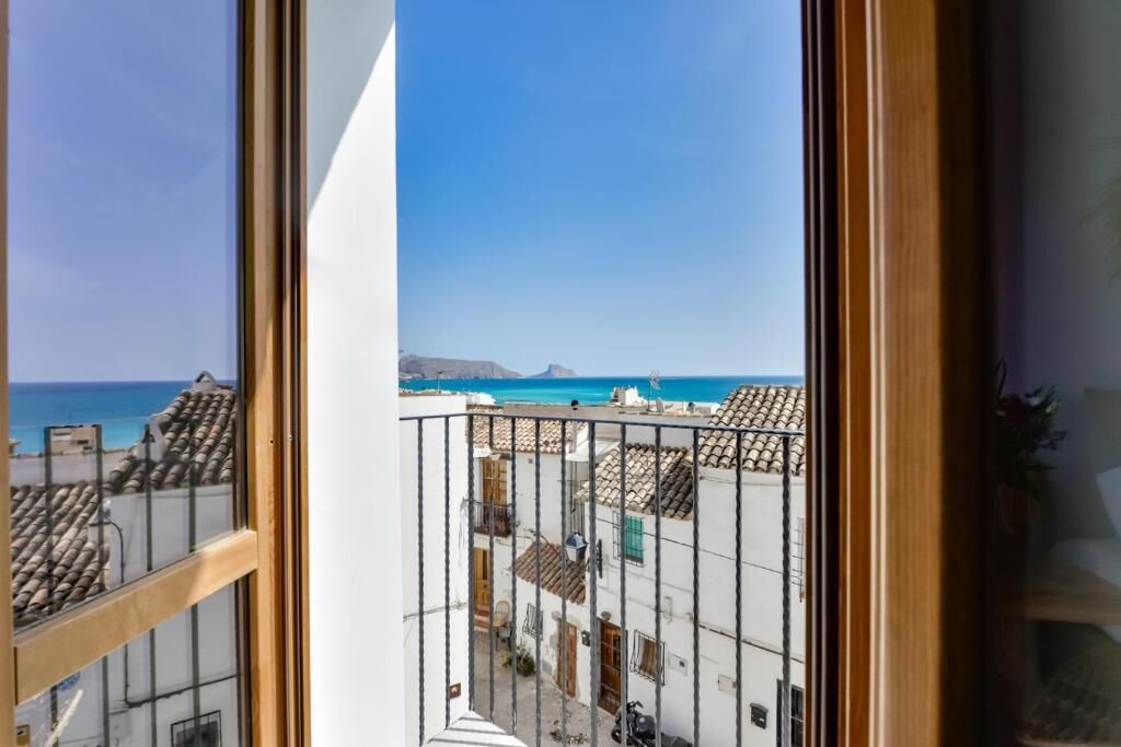 En balkon med udsigt over en kystby og havet.