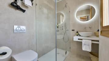 A modern bathroom with a glass-enclosed shower, a white toilet, a sink with a mirror, and a towel hanging on the wall.