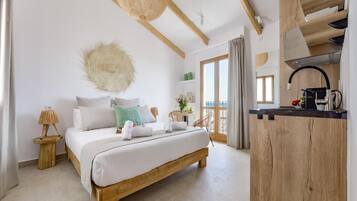 Quarto com cama de madeira, uma mesinha de cabeceira pequena, luminária pendente e vista para a varanda.
