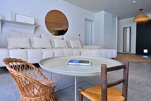 A modern living room with a large sofa, a round glass table, wicker chairs, and a large mirror. - Exceptional villa with Sainte-Victoire view (Aix-en-Provence) next to golf course (Peynier)