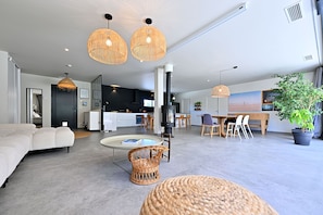 A spacious living area with a sofa, wicker chairs, a round table, and a kitchen in the background. - Exceptional villa with Sainte-Victoire view (Aix-en-Provence) next to golf course (Peynier)