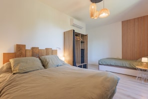 Une chambre moderne avec un grand lit, une armoire et une table de chevet avec une lampe.