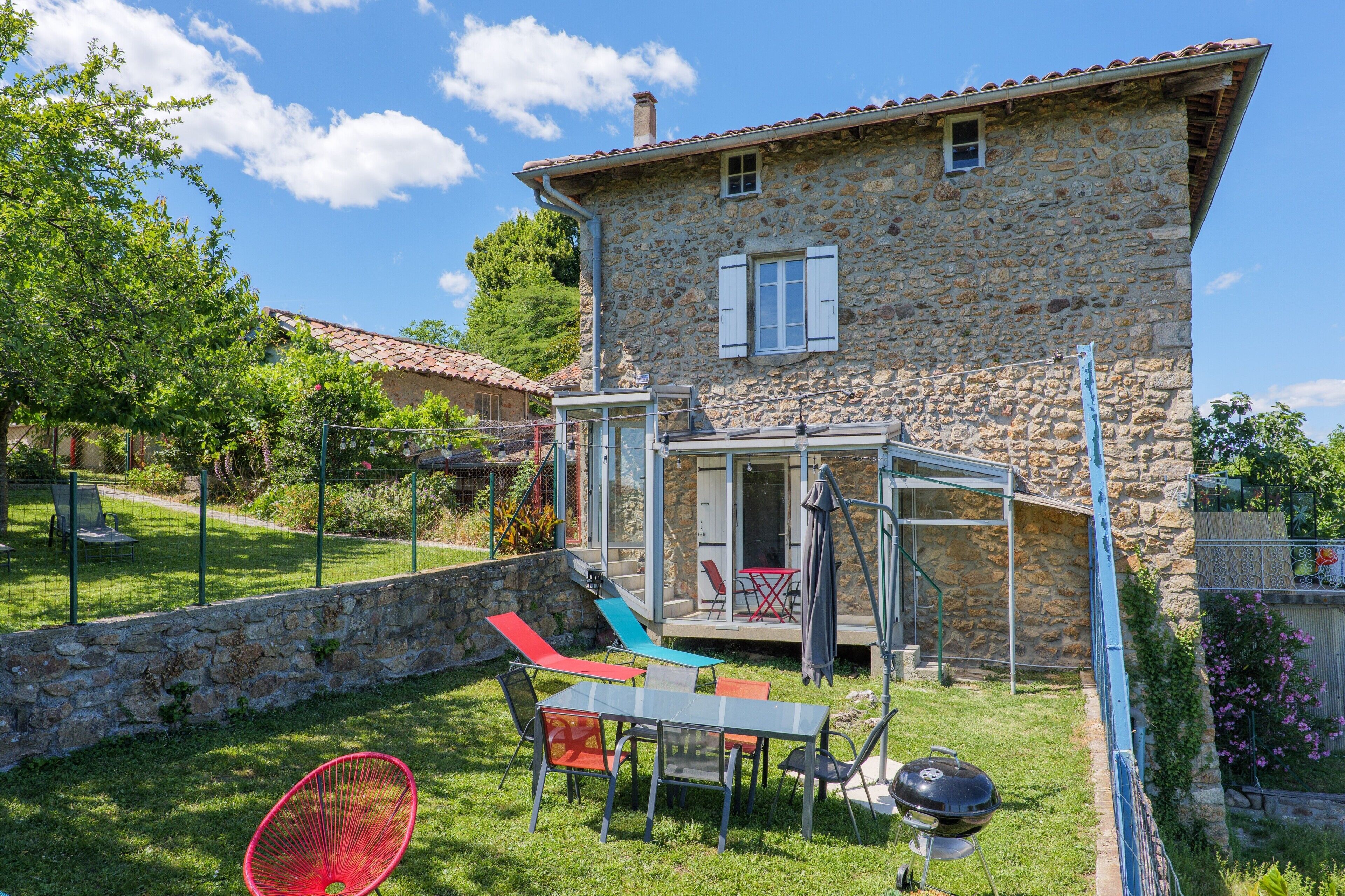 Una casa in pietra con patio, mobili da giardino e una griglia barbecue.