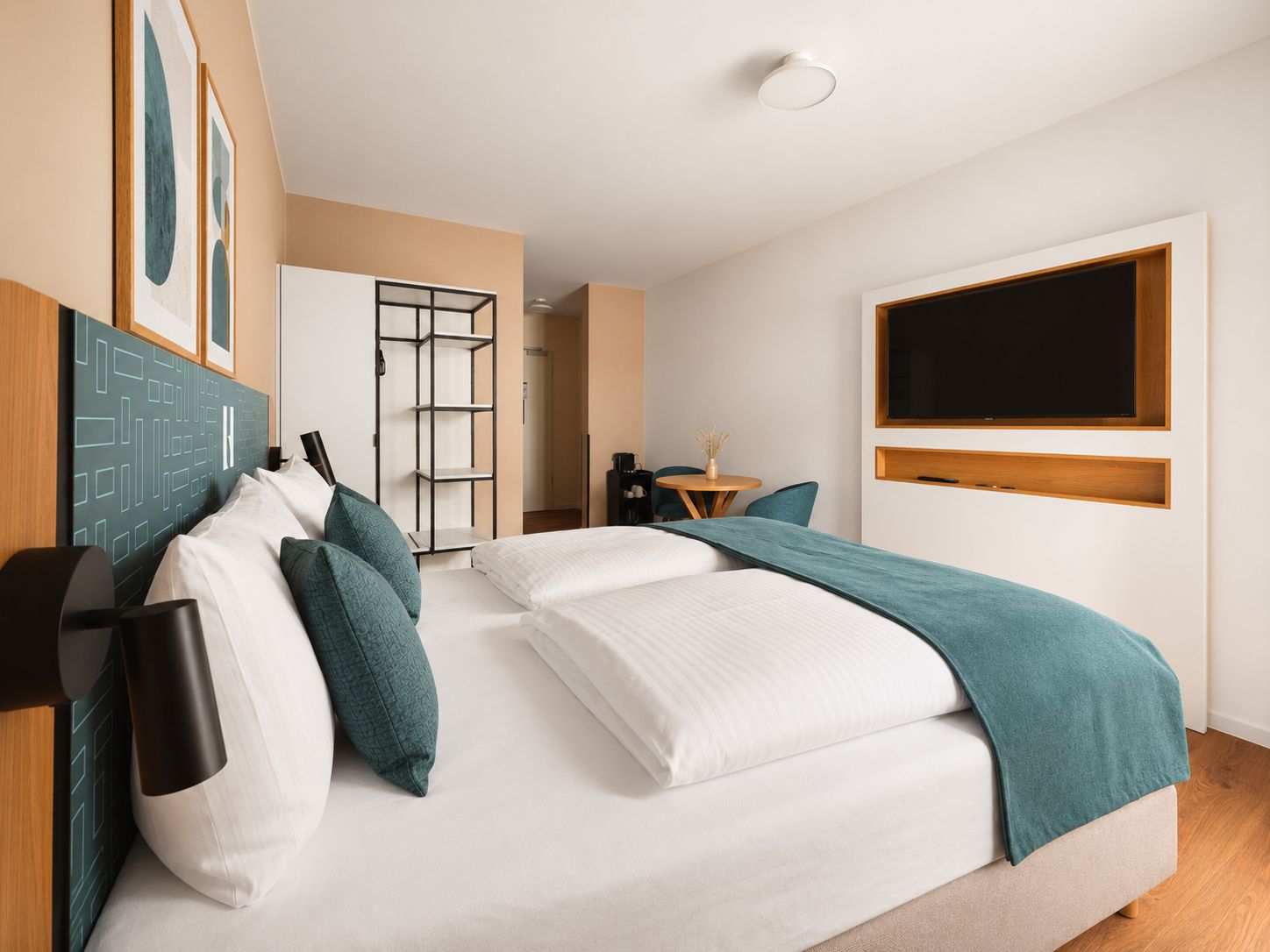 A modern hotel room with a large bed, a desk, and a TV mounted on the wall.