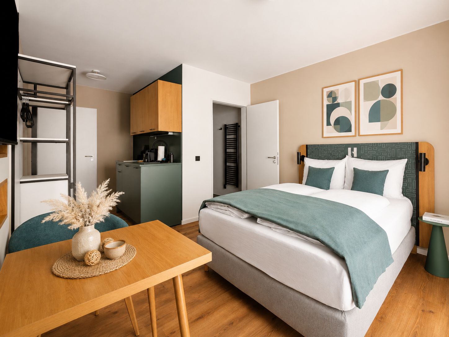 Ein modernes Hotelzimmer mit Bett, Schreibtisch, Küchenzeile und Badezimmer.