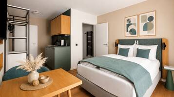 Una habitación de hotel moderna con cama, escritorio, kitchenette y baño.