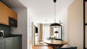 Eine moderne Küche mit Mikrowelle, Kaffeemaschine und Spüle. Ein Essbereich mit rundem Tisch und Stühlen ist ebenfalls vorhanden.