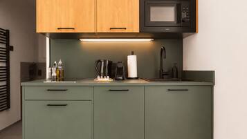 A kitchen with wooden cabinets, a microwave, a coffee maker, and a sink.