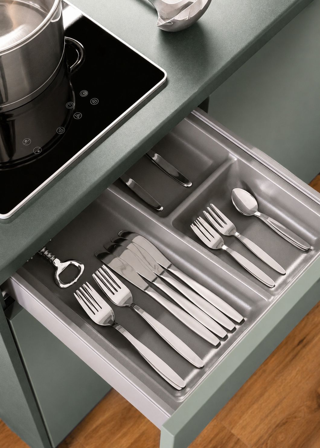 A kitchen with a built-in induction cooktop and a drawer containing neatly arranged utensils.