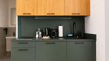 A modern kitchen with a central island, wooden upper cabinets, and a dark green countertop.