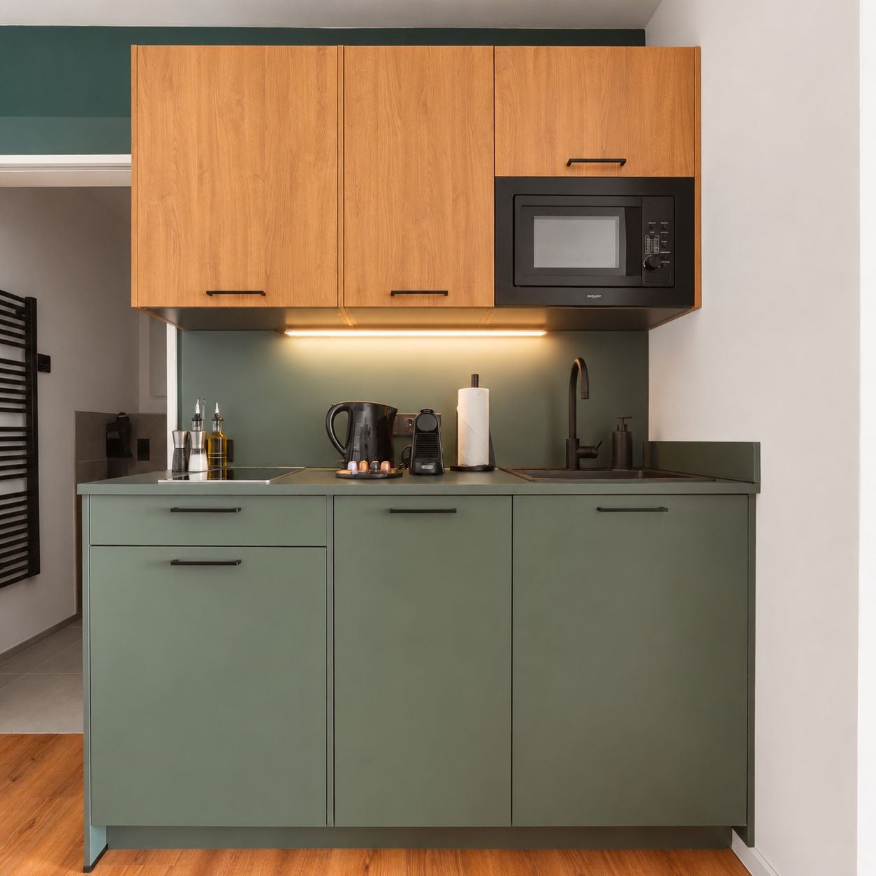A compact kitchen with a microwave, coffee maker, and a kettle on the counter.