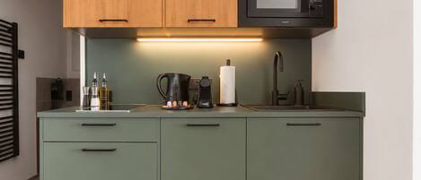 A compact kitchen with a microwave, coffee maker, and a kettle on the counter.