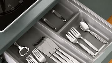 A drawer with kitchen utensils including forks, knives, and a spoon.