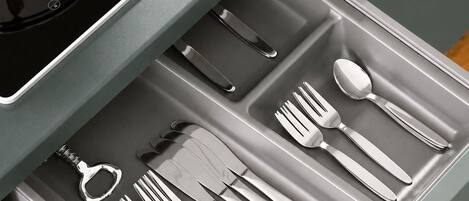 Un cajón con utensilios de cocina, incluyendo tenedores, cuchillos y una cuchara.